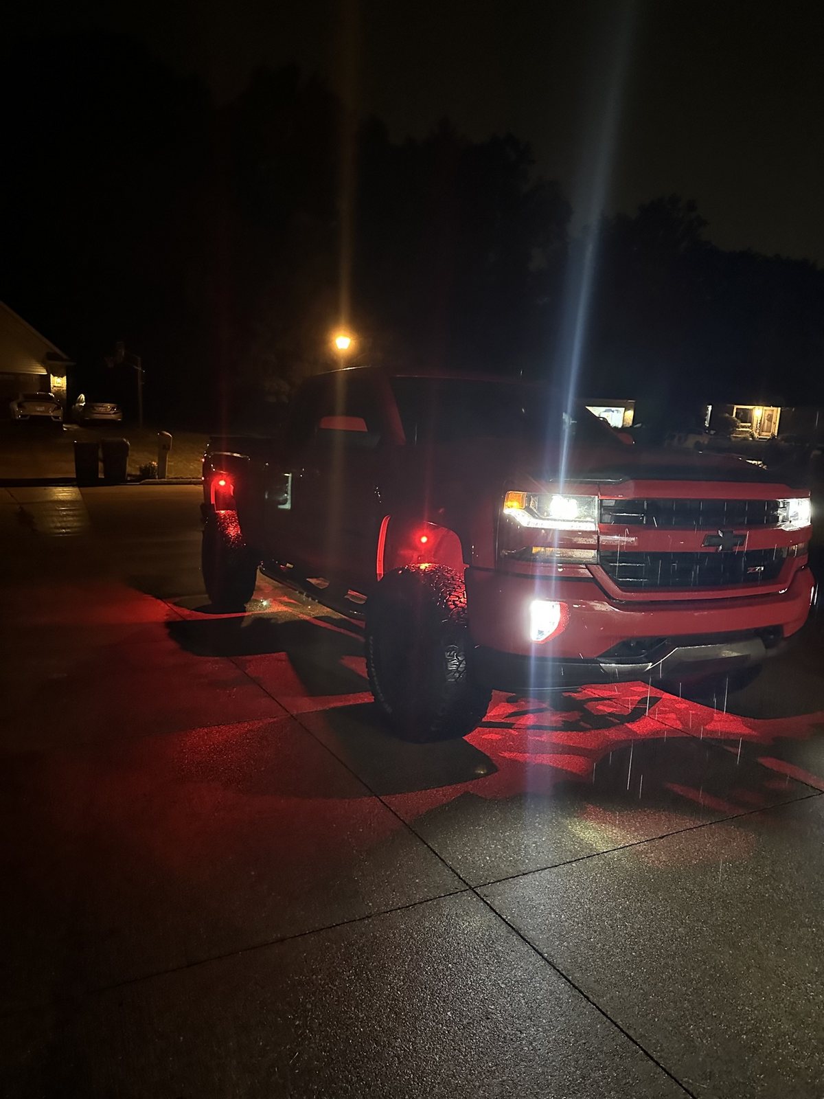Red Silverado at night in the rain with red underglow lighting the ground