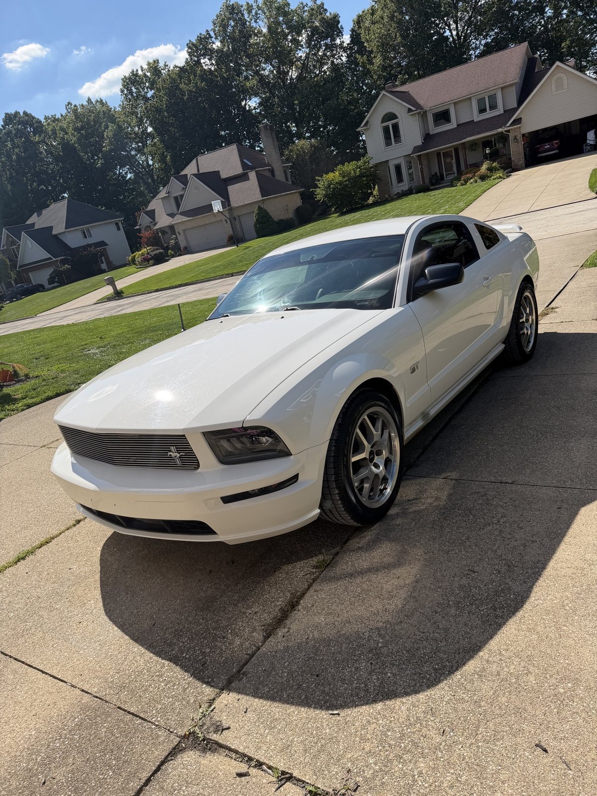 Owner's white 2006 Mustang GT parked on a sunny driveway, front three-quarter view