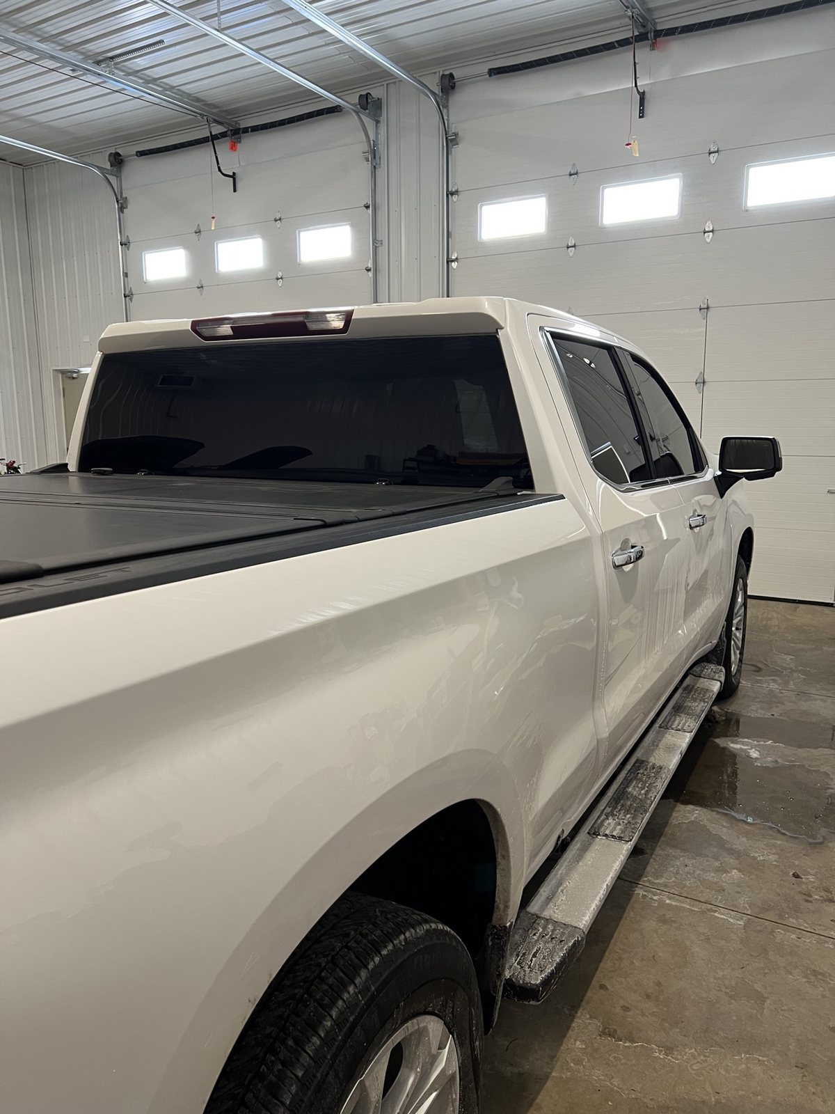 White Silverado rear three-quarter view with dark tinted rear glass and tonneau cover
