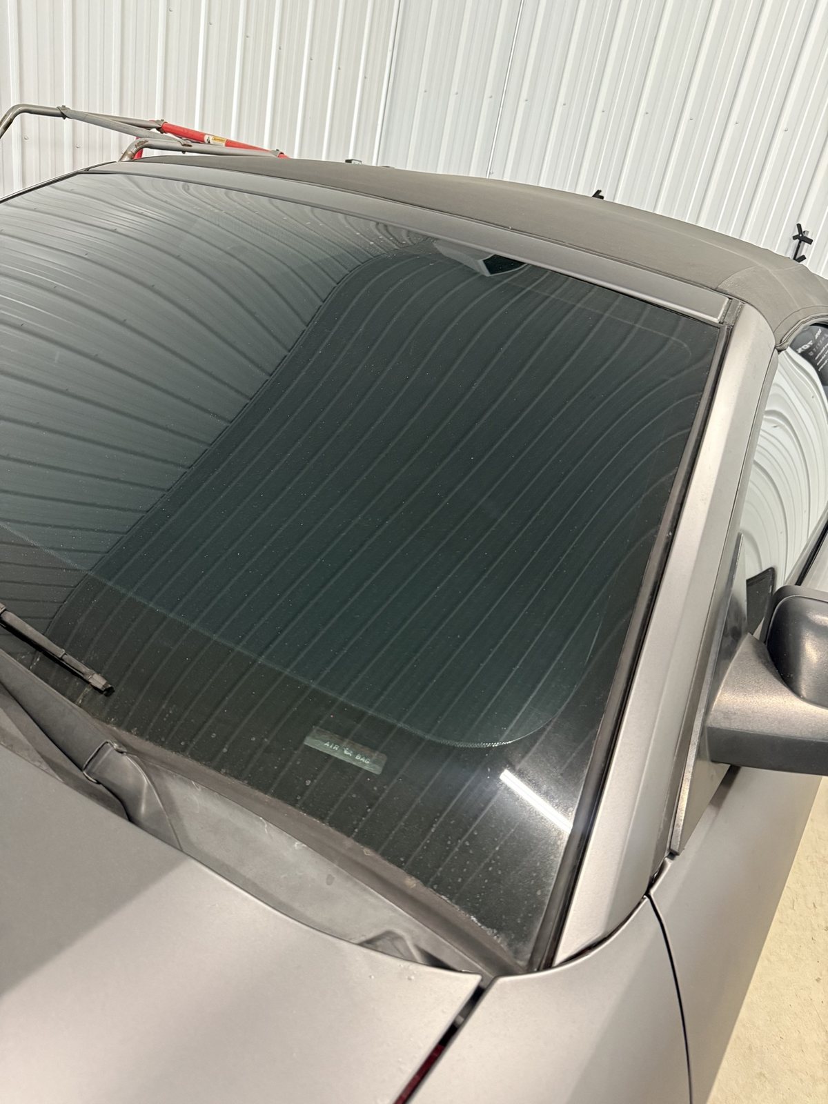 Close-up of a matte grey Mustang convertible windshield with full tint