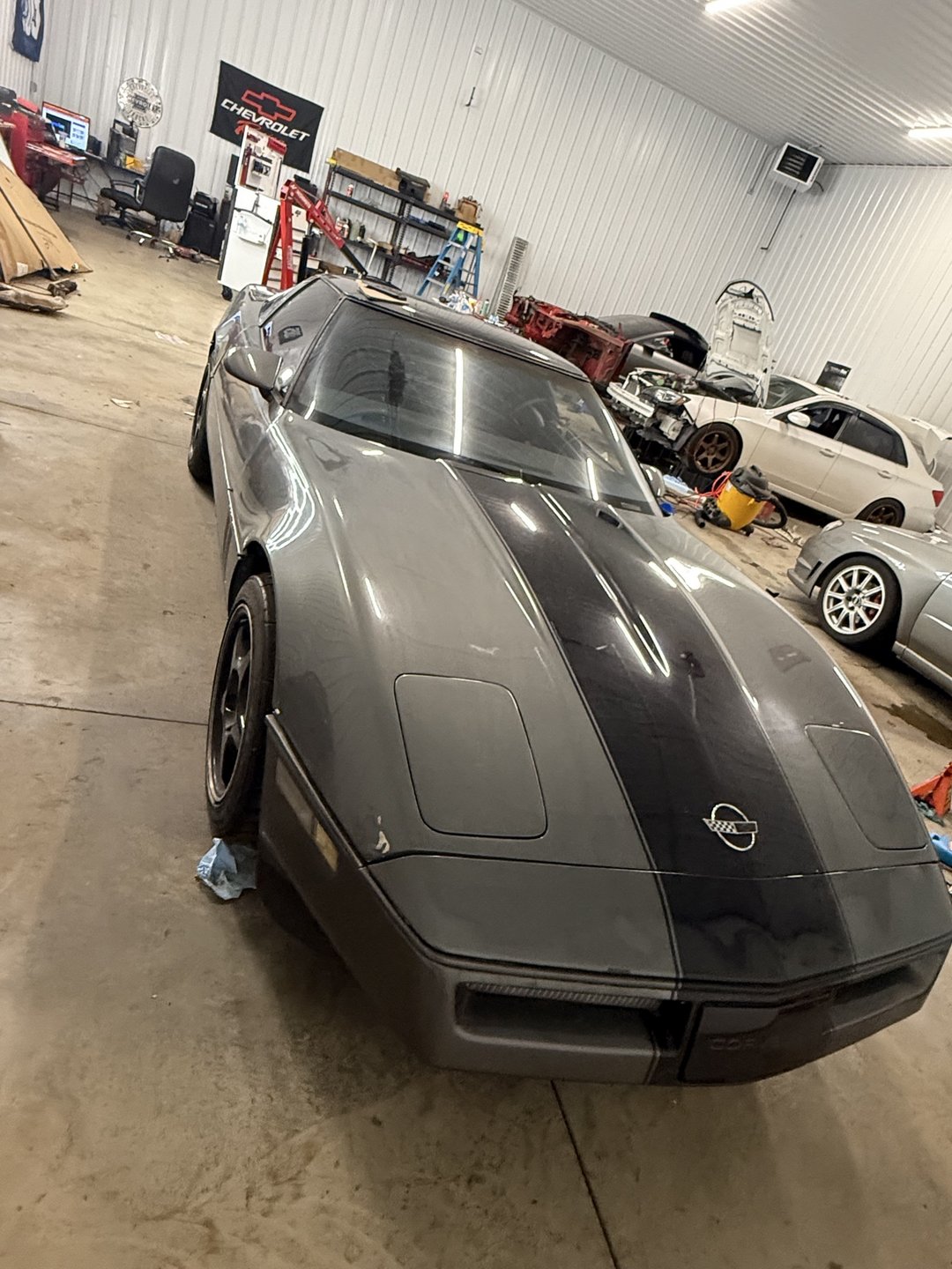 Past shop build — grey 1985 Corvette front view inside the shop