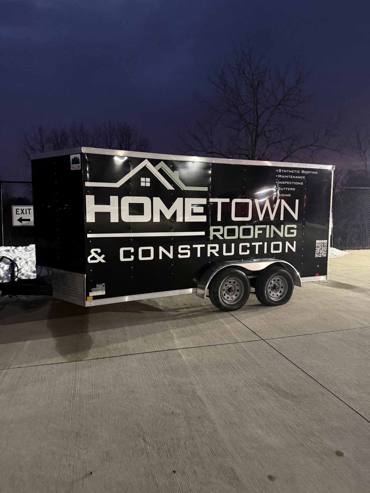 Enclosed trailer wrapped and lettered for Hometown Roofing and Construction at night