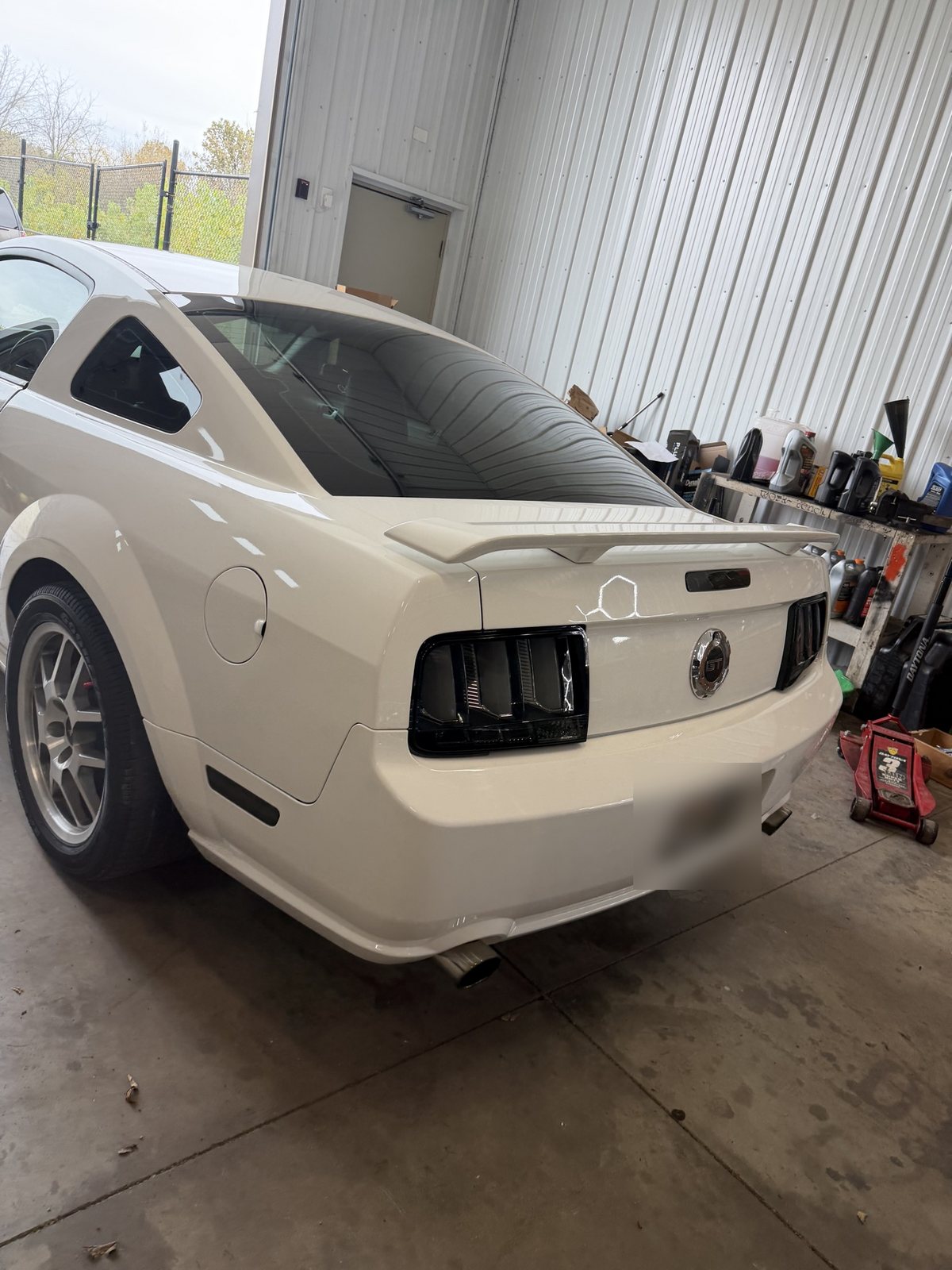 Owner's white 2006 Mustang GT rear three-quarter view in the shop with smoked LED taillights