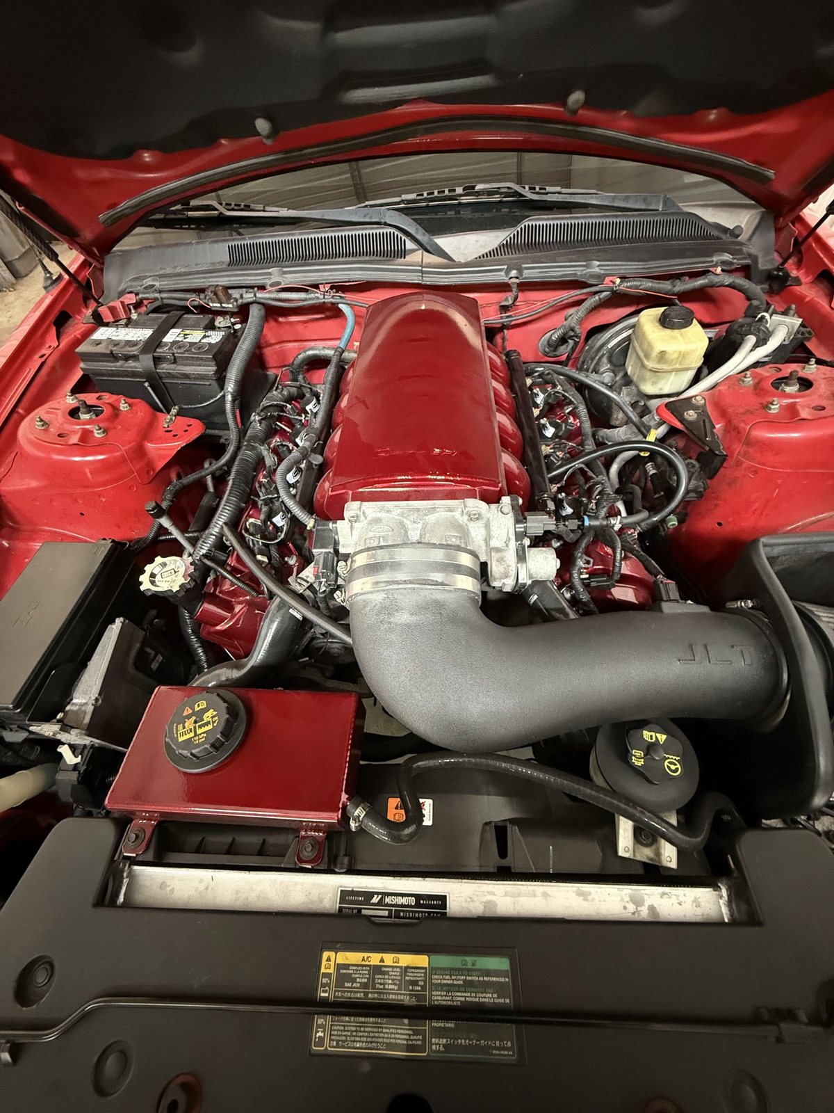 Red Mustang GT engine bay with the candy-red intake installed, JLT intake tube and Mishimoto radiator